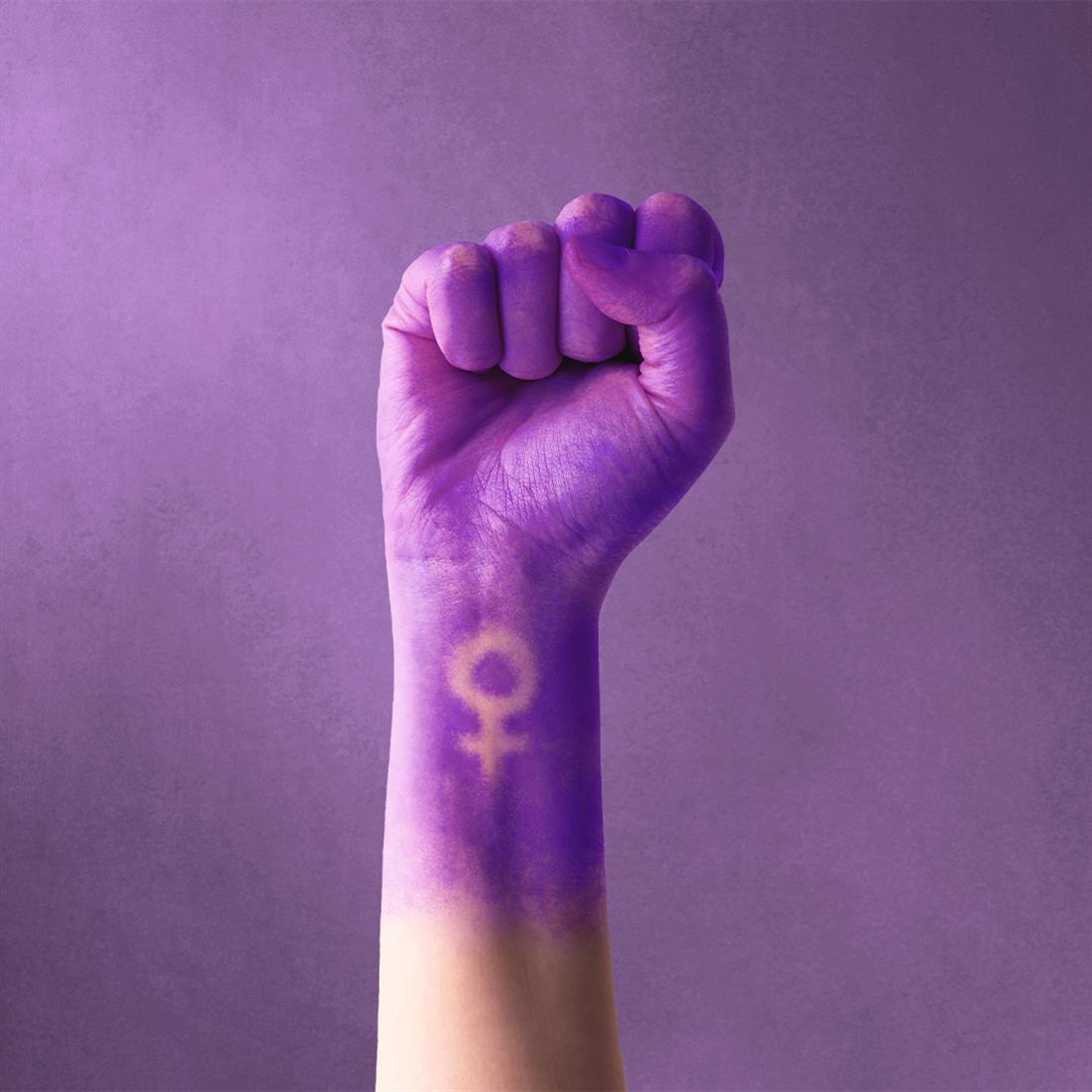 You can see a fist painted purple and raised in the air. The femininity symbol can be seen on the inside of the forearm.
